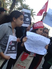 Young women holding signs in support of transitional justice